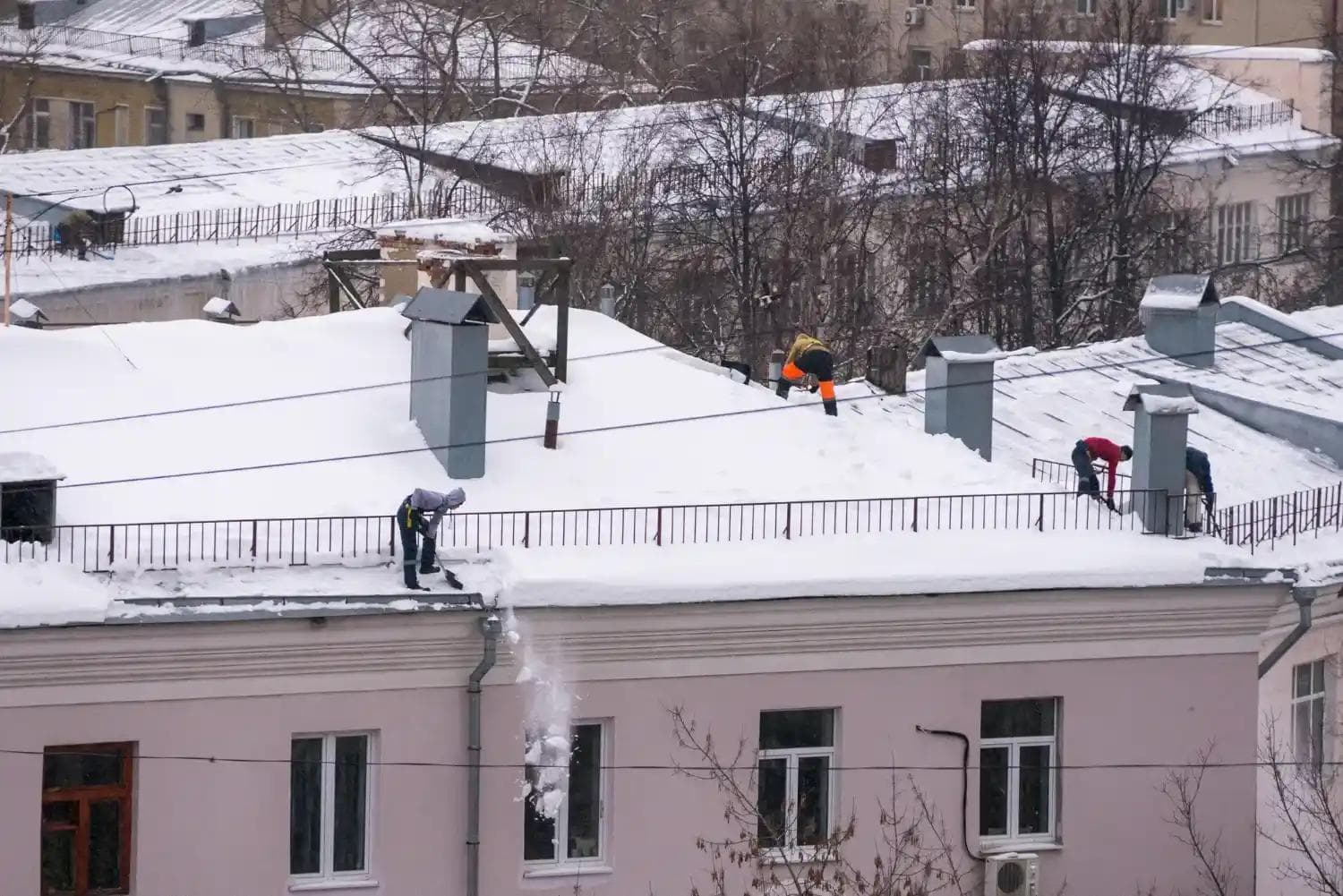 Team shoveling heavy snow from a rooftop, providing essential winter maintenance and snow removal services in Central Oregon.